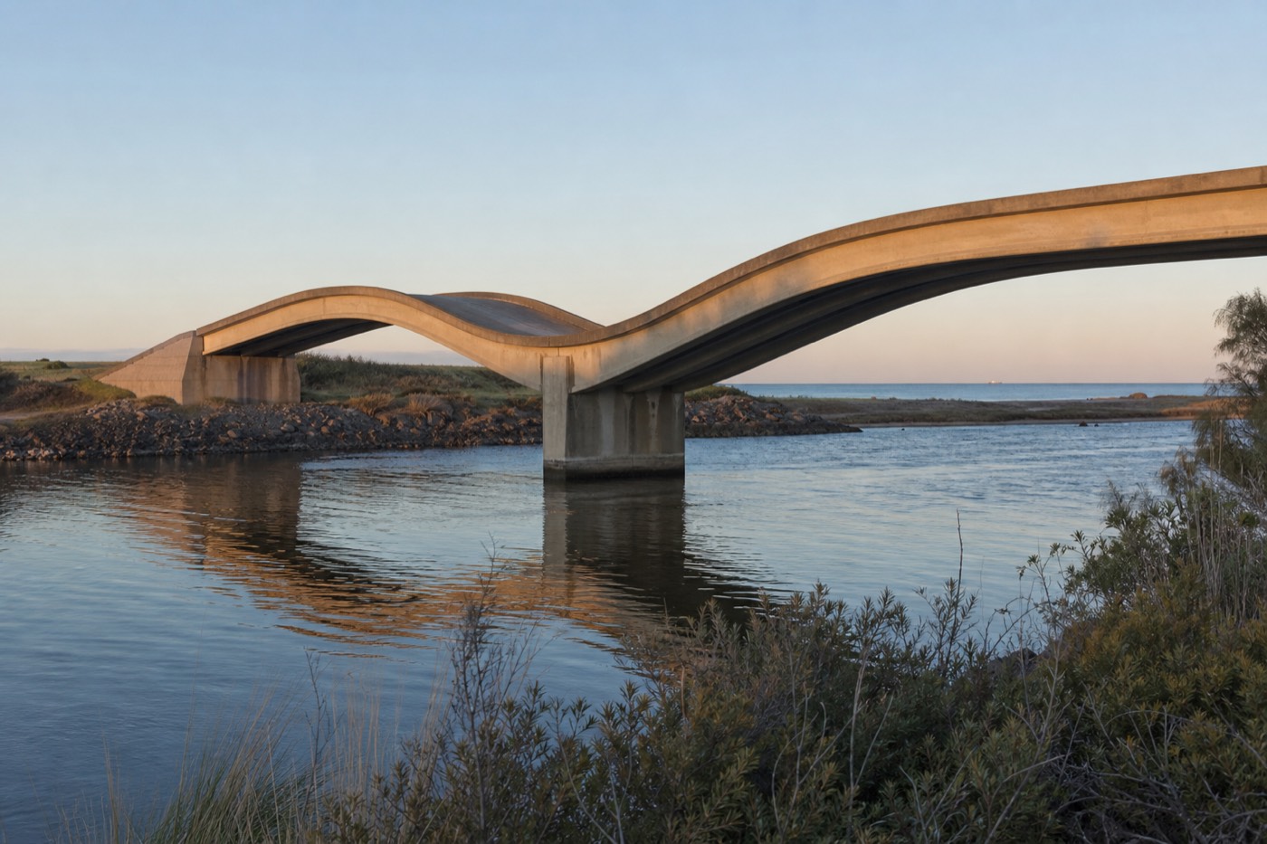 The undulating Leonel Viera bridge dipping and rising across the Maldonado River mouth with small boats moored below and La Barra on the far bank